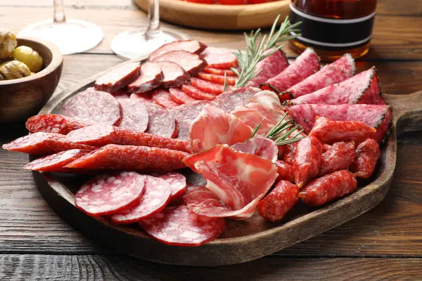 Farklı tütsülenmiş sosisler ahşap masada servis edilir. Yakın plan.