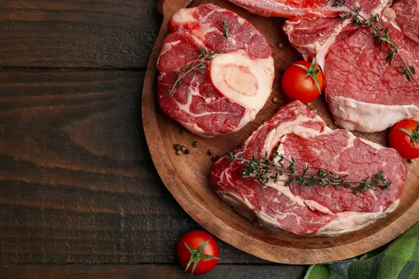 Çiğ et parçaları, baharatlar ve domatesler ahşap masa, üst manzara. Metin için boşluk