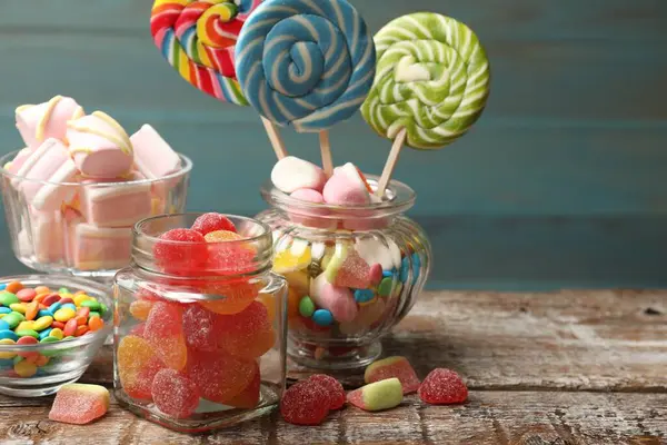 Ahşap masada mavi arka planda farklı lezzetli şekerler. Metin için boşluk