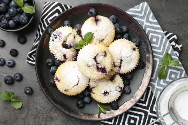 Yaban mersinli lezzetli çörekler, pudra şekeri ve siyah desenli masada nane şekeri.