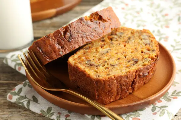 Ev yapımı havuçlu kek, fındıklı ve çatallı, ahşap masa, yakın plan.