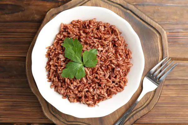 Ahşap masada servis edilen maydanozlu lezzetli kahverengi pirinç.