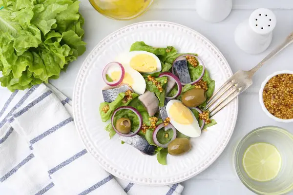 Ringa balıklı lezzetli salata, yumurta, hardal ve sebzeler beyaz fayanslı masada servis edilir.