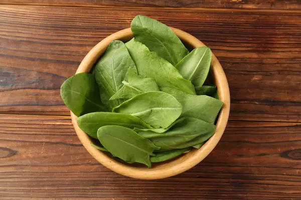 Taze yeşil kuş yaprakları kasede, ahşap masada, üst tarafta.