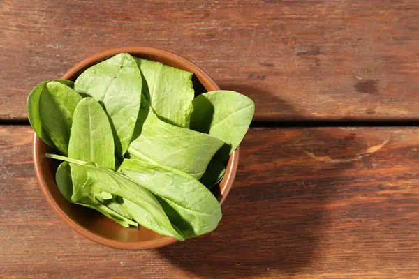 Tahta masadaki kasede taze yeşil kuş yaprakları, üst manzara. Metin için boşluk