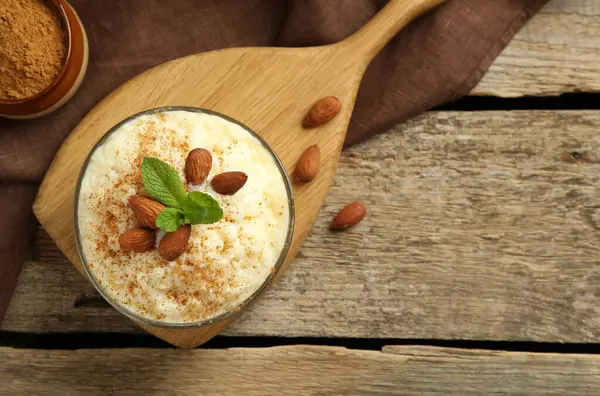 Tarçınlı sütlaç, badem ve nane şekerli ahşap masa, üst manzara. Metin için boşluk