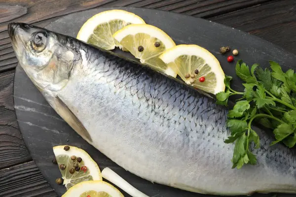 Ahşap masada tuzlanmış ringa balığı ve baharat, üst manzara.