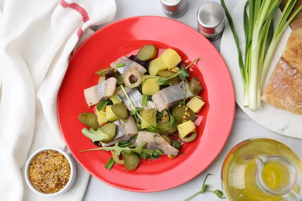 Ringa balıklı nefis salata ve beyaz fayanslı masada malzemeler, düz konum