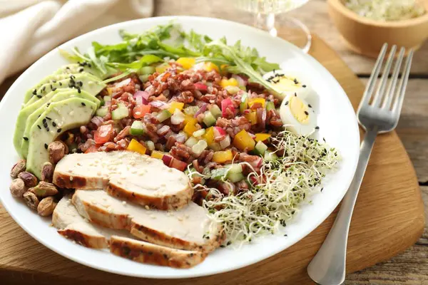 Tahta masada servis edilen kahverengi pirinçli lezzetli salata, yakın plan.