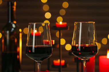Glasses of red wine against blurred background, closeup. Romantic dinner