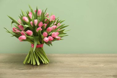 Tahta masadaki güzel laleler soluk yeşil arka planda, metin için yer var.