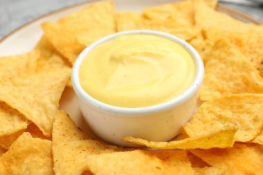 Lezzetli peynir sosu kasede ve cipsler masada, yakın plan.