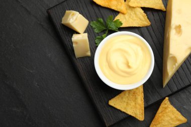 Lezzetli bir peynir sosu, siyah masada nacho cipsi ve maydanoz, üst manzara. Metin için boşluk