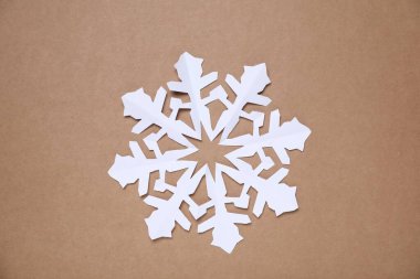 Kahverengi arka planda bir kağıt kar tanesi, üst manzara