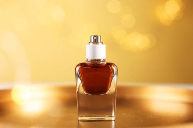 Bir şişe aromatik parfüm metal tepside bej arka planda bulanık ışıklarla, yakın plan. Bokeh etkisi