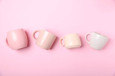 Pembe arka planda bir sürü renkli fincanlar var.