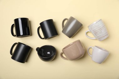 Soluk sarı arka planda birçok farklı fincan, düz uzandı.