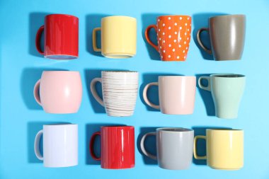 Açık mavi arkaplanda bir sürü renkli fincan, düz yatıyordu.