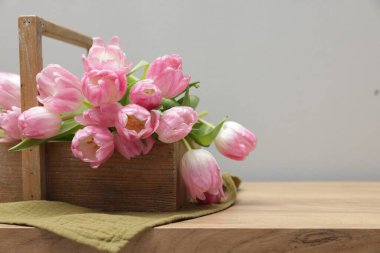 Güzel laleler sepetin içinde, ahşap masada, gri arka planda, yakın plan. Metin için boşluk