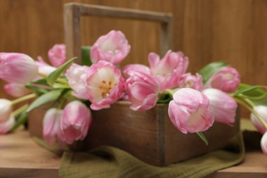 Güzel laleler sepetin içinde, ahşap masada, yakın plan.