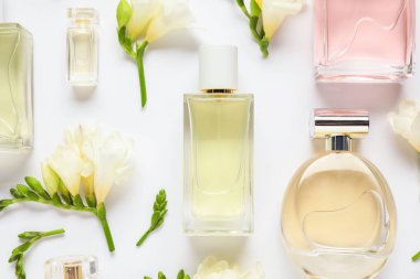 Parfüm şişeleri ve beyaz arka planda güzel çiçekler.