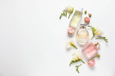 Düz kompozisyonda aromatik parfüm şişeleri ve beyaz arka planda güzel çiçekler vardı. Metin için boşluk