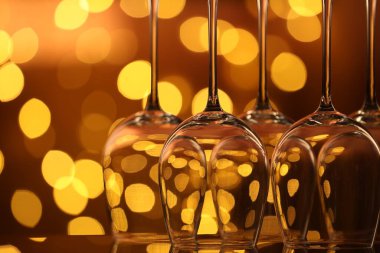 Bulanık ışıklara karşı cam ayna yüzeyinde birçok temiz bardak, yakın plan. Bokeh etkisi