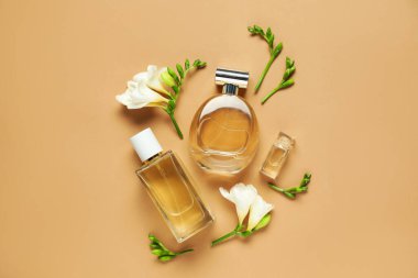 Düz kompozisyonda aromatik parfüm şişeleri ve bej arka planda güzel çiçekler vardı.