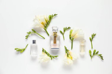 Düz kompozisyon, beyaz arka planda aromatik parfüm şişeleri ve güzel çiçekler vardı.