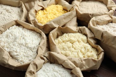 Tahta masadaki kağıt torbalarda farklı türde un, yakın plan.