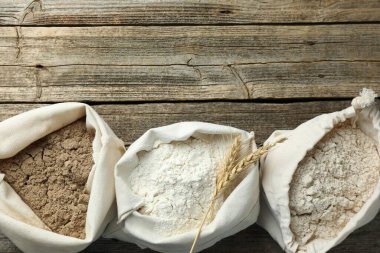 Tahta masadaki poşetlerdeki farklı un türleri, düz yatış. Metin için boşluk