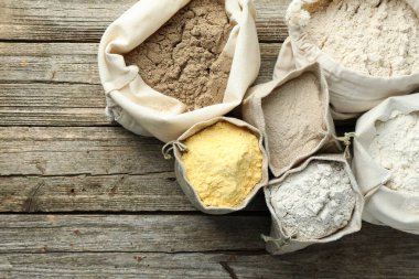 Tahta masadaki poşetlerdeki farklı un türleri, düz yatış. Metin için boşluk