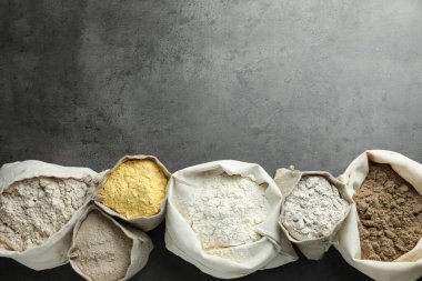 Gri masadaki poşetlerdeki farklı tipte un, düz. Metin için boşluk