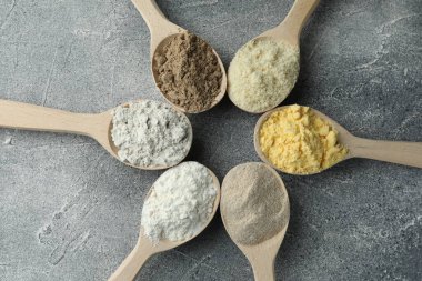 Gri masadaki kaşıklarda farklı türde un, düz.