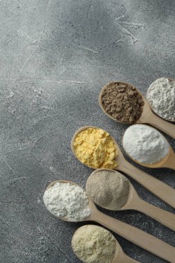 Gri masadaki kaşıklarda farklı türde un, düz. Metin için boşluk