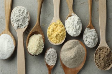 Açık gri masadaki kaşıklarda farklı türde un, düz.