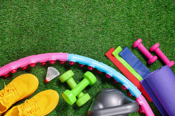 Разные тренажерные принадлежности на искусственной зеленой траве, плоский пол. Пространство для текста