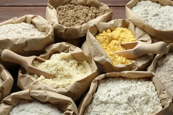 Tahta masadaki kağıt torbalarda farklı türde un, yakın plan.