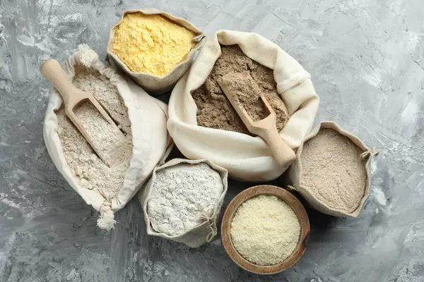 Gri desenli sehpada, düz yerde duran farklı tipte un var.