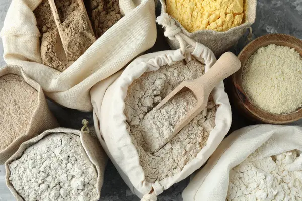 Gri desenli sehpada, düz yerde duran farklı tipte un var.