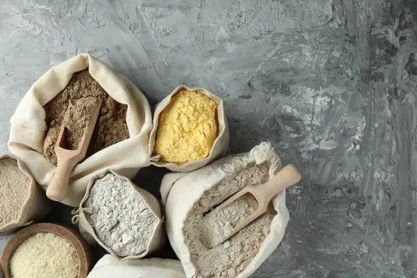 Gri desenli masa ve düz yatak üzerinde farklı tipte un torbaları. Metin için boşluk