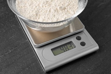 Elektronik mutfak terazisi ve koyu dokulu bir kase un, yakın plan.