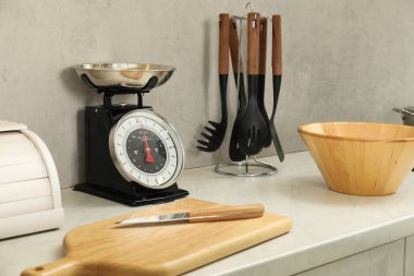 Retro mechanical kitchen scale and other utensils on white marble countertop indoors