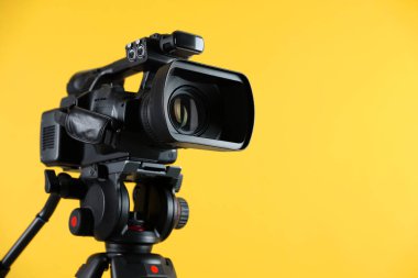 Sarı arka planda modern video kamera, yakın plan. Metin için boşluk