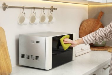 Mutfakta halı ile mikrodalga fırını temizleyen kadın, yakın plan.