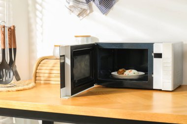 Mikrodalga fırını aç, pilav ve tavukla birlikte ahşap masa içinde.