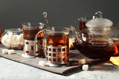 Gri dokulu masada servis edilen metal tutacaklı çay bardakları.