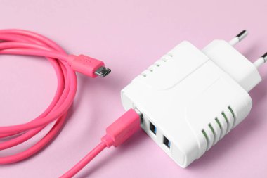Pembe arka planda şarj kablosu olan USB güç adaptörü, kapat