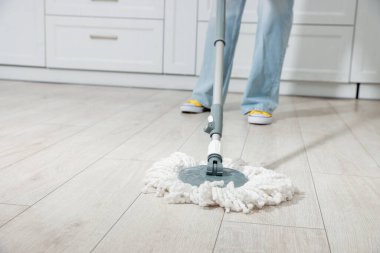 Evdeki yerleri paspasla temizleyen kadın, yakın plan. Metin için boşluk