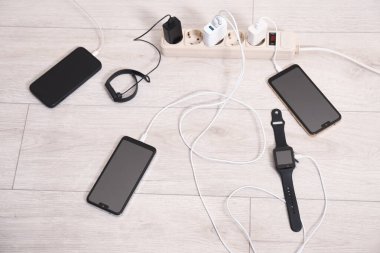 Kablolu USB adaptörleri ahşap zemindeki güç kablosu şarj cihazlarına bağlı, üst görünümde.